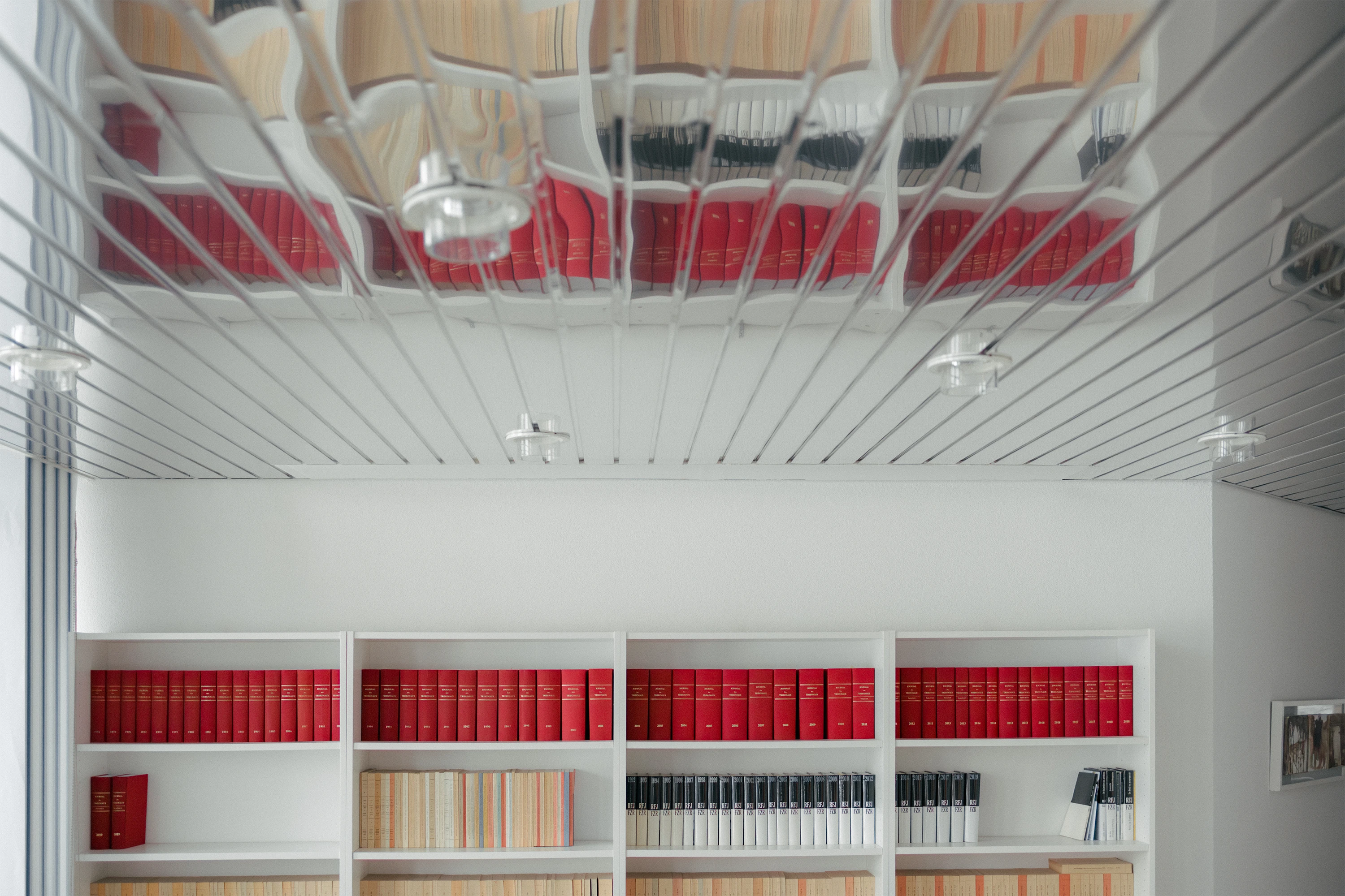 Une armoire remplie de livre juridique vue au travers de la réflection du plafond.